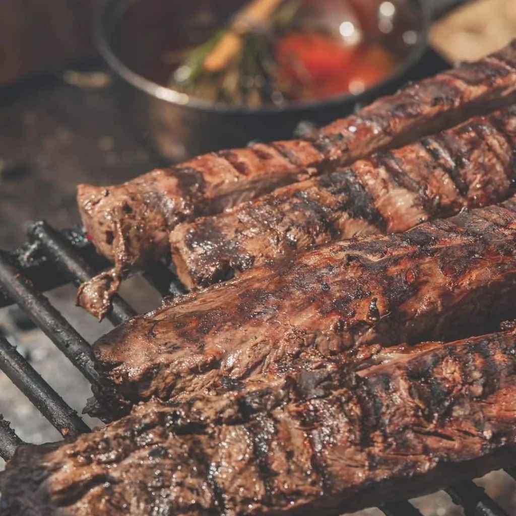 Beautifully charred ribs cooking over an open fire grill