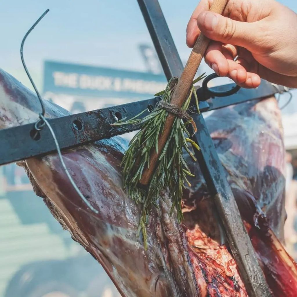 Basting meat on an Argentine cross with a fresh rosemary brush
