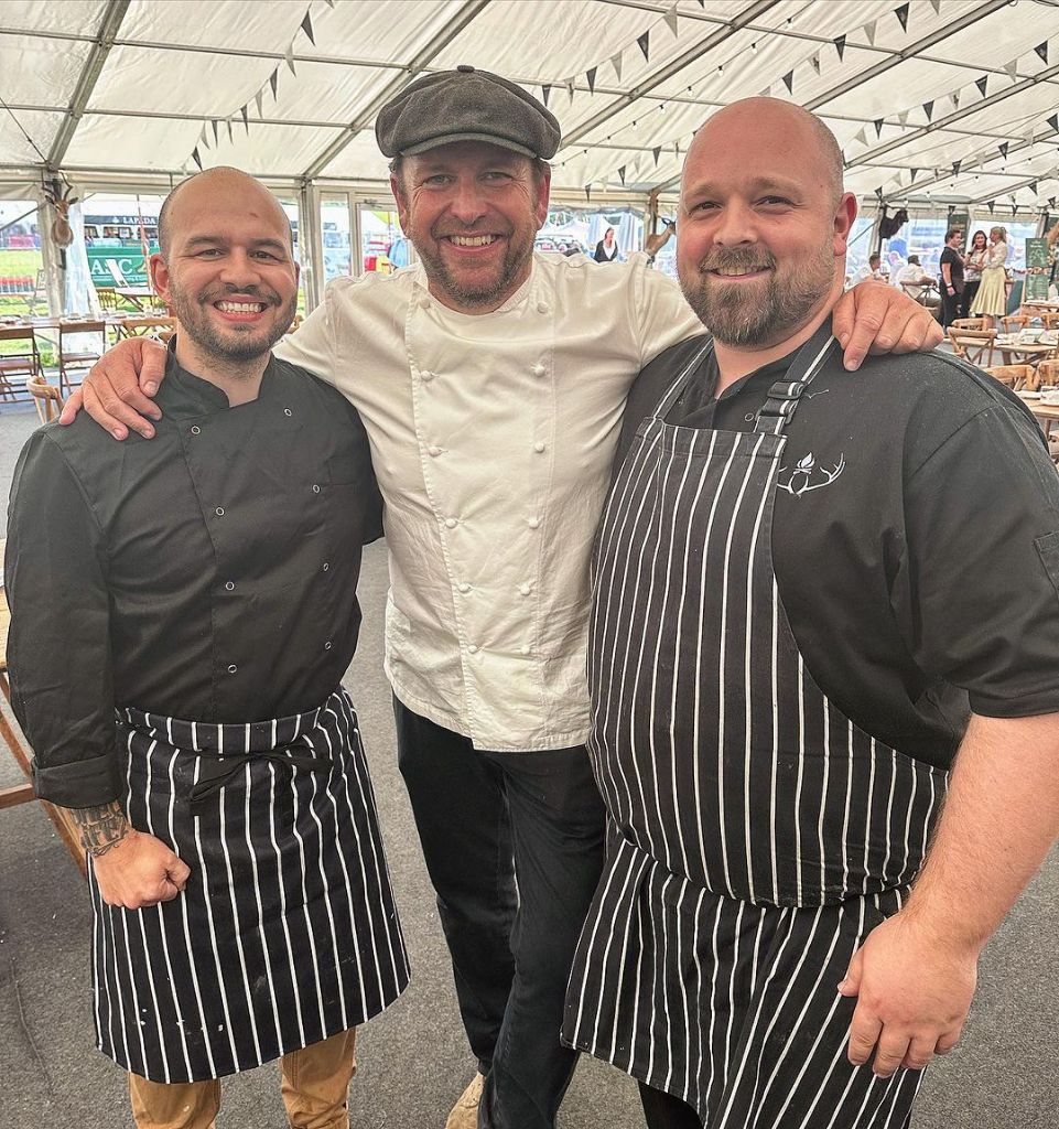 Three Game and Flames chefs in striped aprons at a marquee event