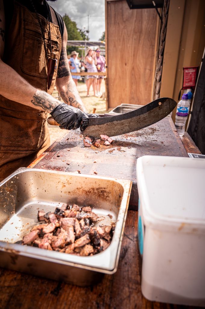 Chef chopping smoked meat with a cleaver at a festival event