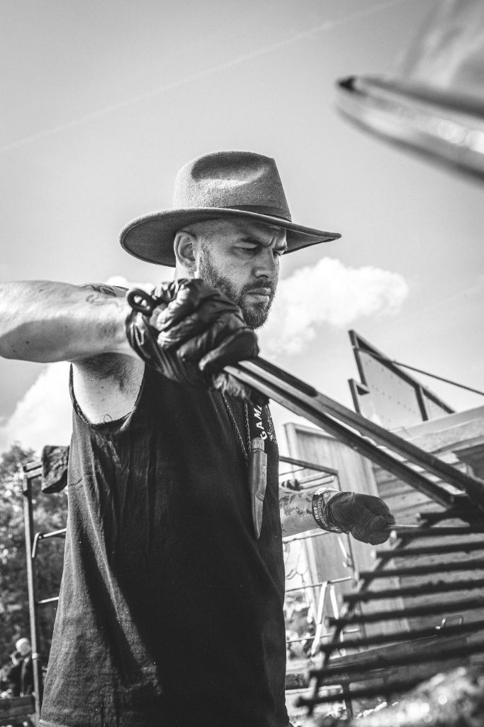 Cai Ap Bryn in black and white holding tongs at a festival