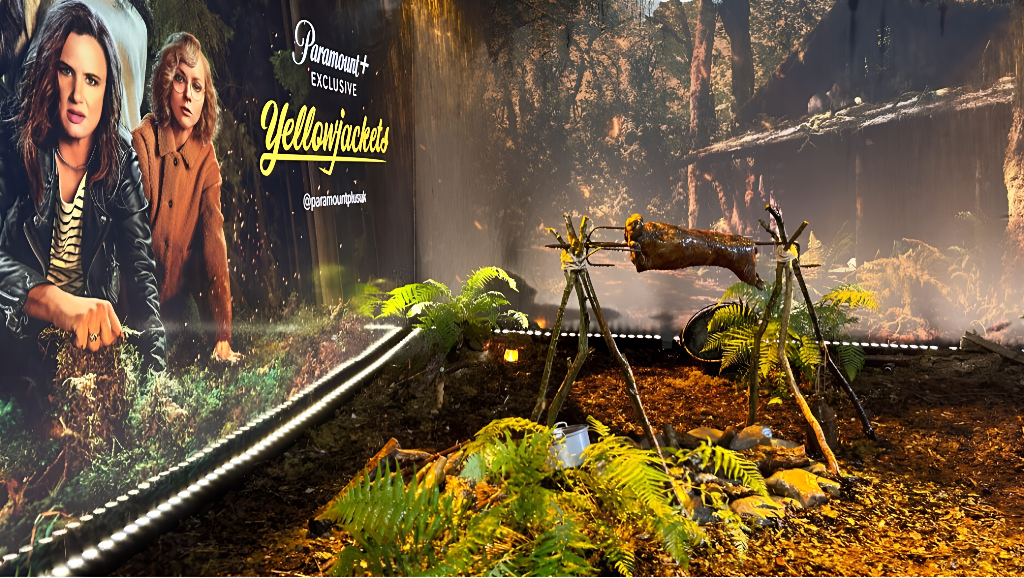 Paramount+ Yellowjackets Season 2 launch event - themed wilderness set with spit-roast and fern-covered forest floor