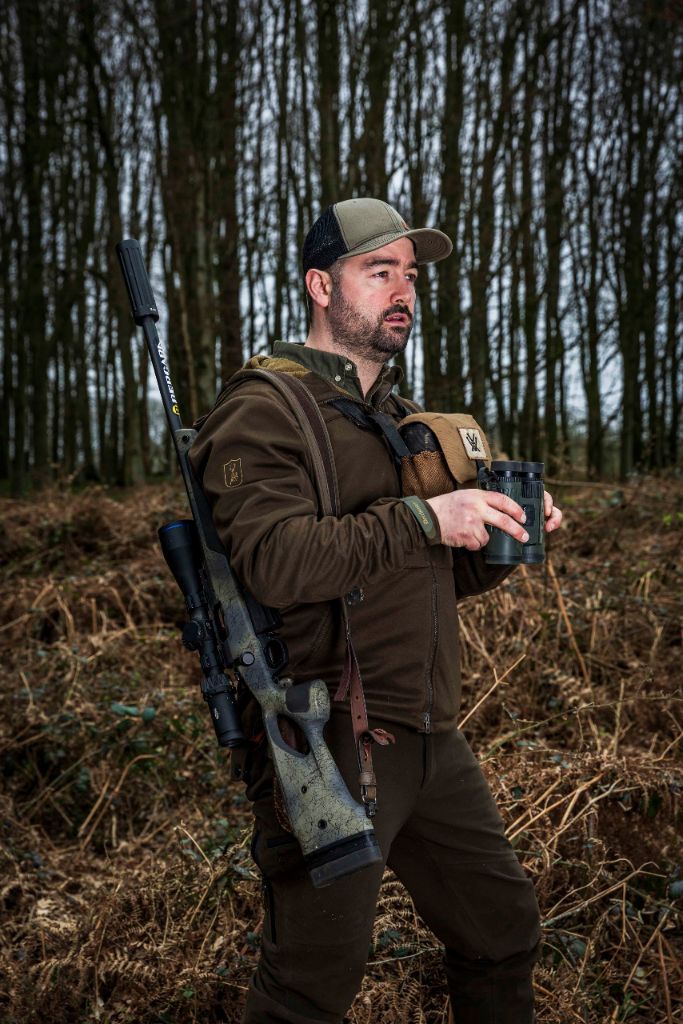 Cai scanning woodland with binoculars while out stalking