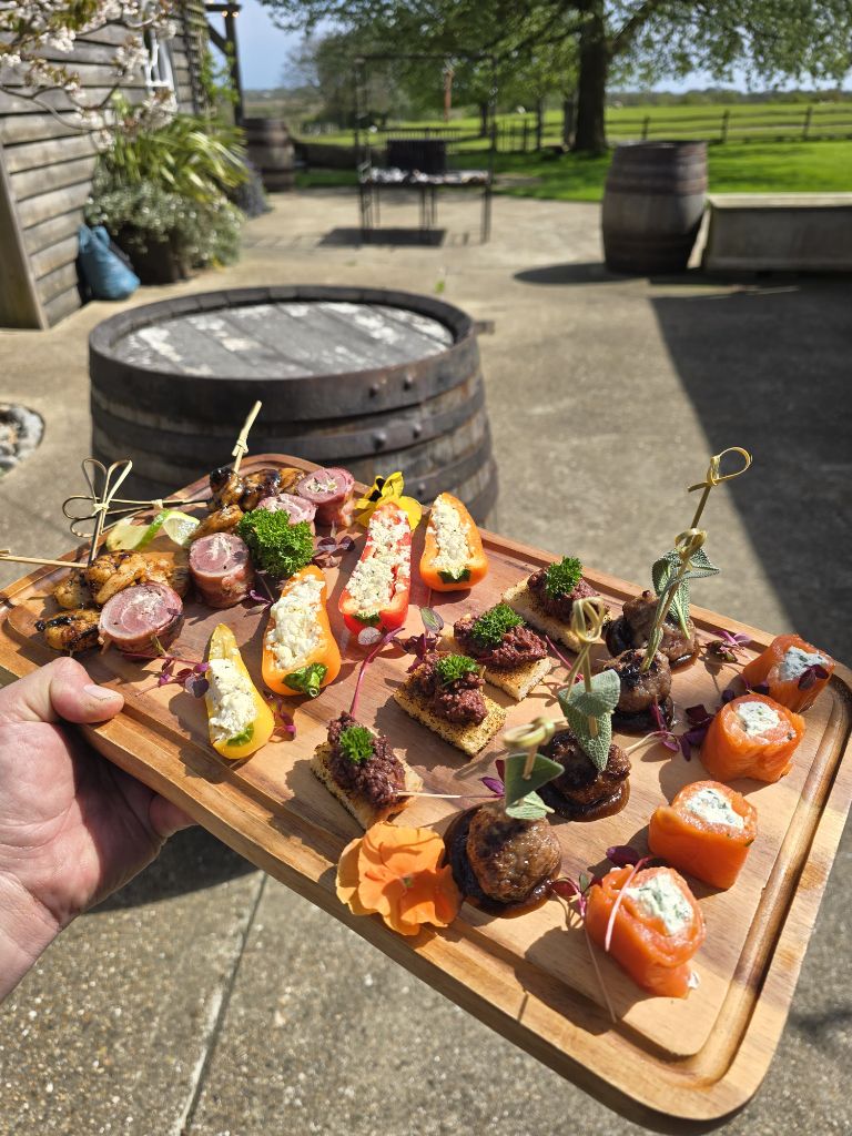 Mixed canape board with skewers, stuffed peppers, tartare and salmon roulades by a wine barrel