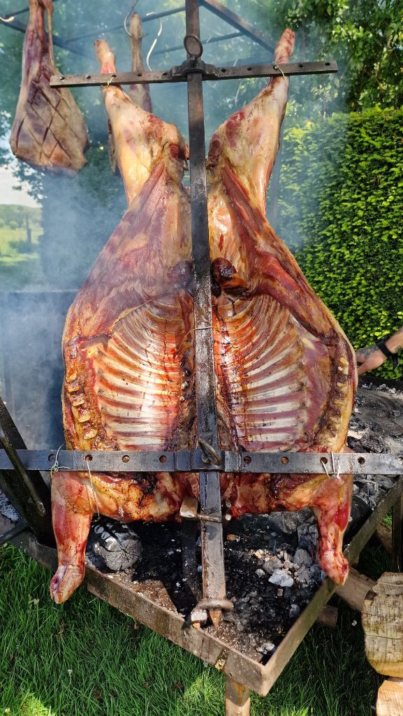 Whole animal roasting on iron fire frame at a Game and Flames wedding